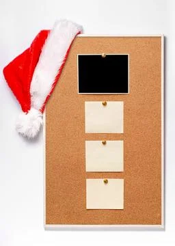 Blank paper notes and an empty photo are pinned to a cork board. Santas hat on a Stock Photos
