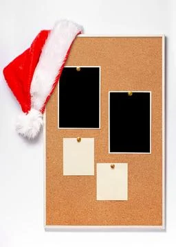 Blank paper notes and an empty photo are pinned to a cork board. Santa's ha.. Stock Photos