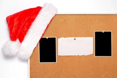 Blank paper notes and an empty photo are pinned to a cork board. Santa's hat  Stock Photos