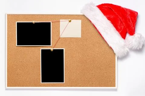 Blank paper notes and an empty photo are pinned to a cork board. Santa's ha.. Stock Photos