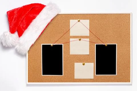 Blank paper notes and an empty photo are pinned to a cork board. Santa's ha.. Stock Photos