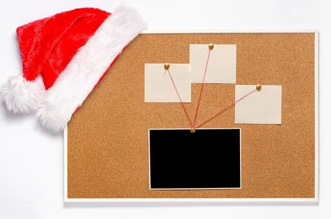 Blank paper notes and an empty photo are pinned to a cork board. Santa's ha.. Stock Photos