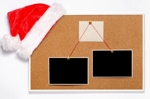 Blank paper notes and an empty photo are pinned to a cork board. Santa's ha.. Stock Photos
