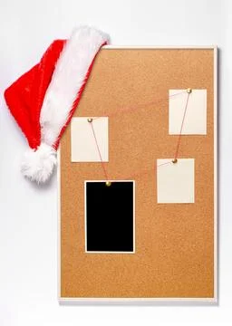 Blank paper notes and an empty photo are pinned to a cork board. Santa's ha.. Stock-Fotos