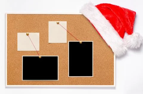 Blank paper notes and an empty photo are pinned to a cork board. Santas hat on a Stock Photos