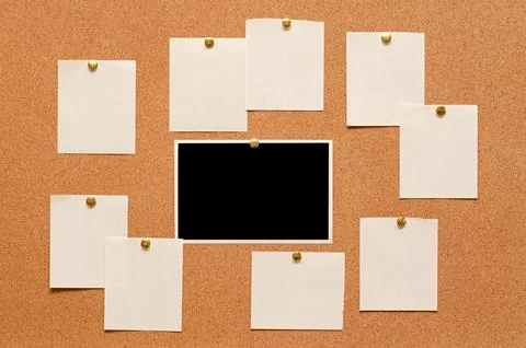 Blank paper notes and an empty photo are pinned to a cork board. The concept of Stock Photos