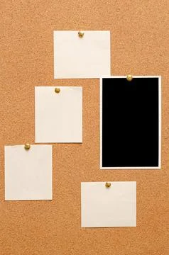 Blank paper notes and an empty photo are pinned to a cork board. The concept of Stock Photos