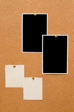 Blank paper notes and an empty photo are pinned to a cork board. The concept of Stock Photos