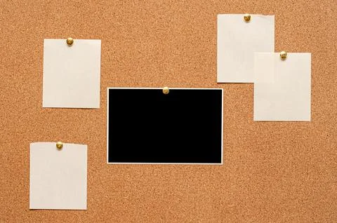 Blank paper notes and an empty photo are pinned to a cork board. The concep.. Stock Photos