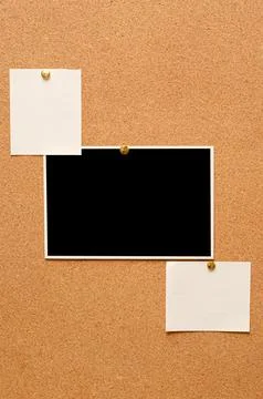 Blank paper notes and an empty photo are pinned to a cork board. The concep.. Stock Photos