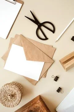 Blank paper sheet with envelope on beige table. Artist home office desk works Stock Photos