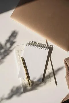 Blank paper sheet notebook with copy space, flower sunlight shadows and lapto Fotos de archivo