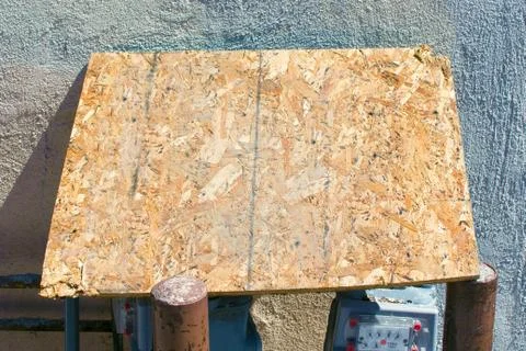 Blank Particle Board propped on two metal Poles in front of Concrete Wall Stock Photos