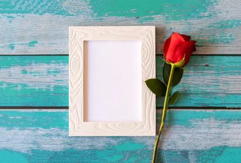Blank photo frame and red roses over wooden table Stock Photos