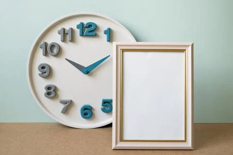 Blank picture frame with clock on brown shelf. mint wall background Stock Photos
