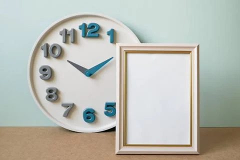Blank picture frame with clock on brown shelf. mint wall background. copy ... Stock Photos