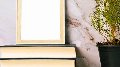 Blank picture frame on stack of books next to a potted plant Stock Photos