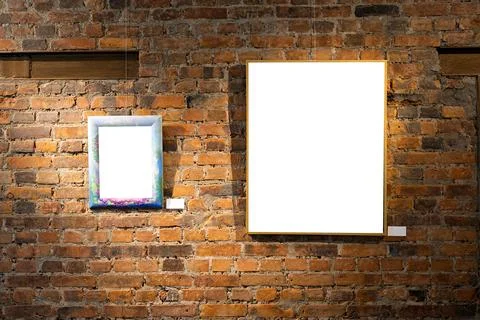 Blank picture frames on brick wall with glowing lamp, mock up Stock Photos