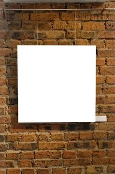 Blank picture frames on brick wall with glowing lamp, mock up Stock Photos