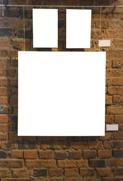 Blank picture frames on brick wall with glowing lamp, mock up Stock Photos