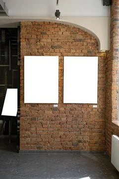 Blank picture frames on brick wall with glowing lamp, mock up Stock Photos
