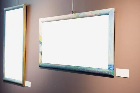 Blank picture frames on brown wall with glowing lamp, mock up Stock Photos