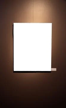 Blank picture frames on brown wall with glowing lamp, mock up Stock Photos