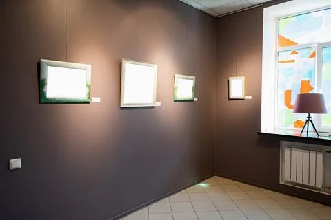 Blank picture frames on brown wall with glowing lamp, mock up Stock Photos