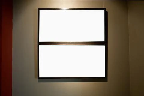 Blank picture frames on brown wall with glowing lamp, mock up Stock Photos