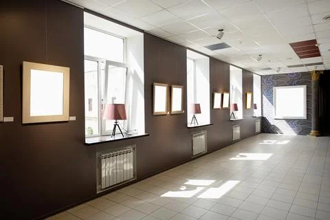 Blank picture frames on brown wall with glowing lamp, mock up Stock Photos