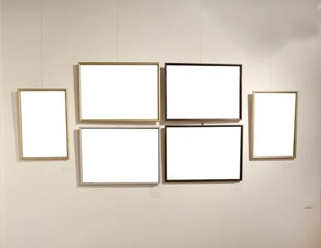 Blank picture frames on grey wall with glowing lamp, mock up Stock Photos