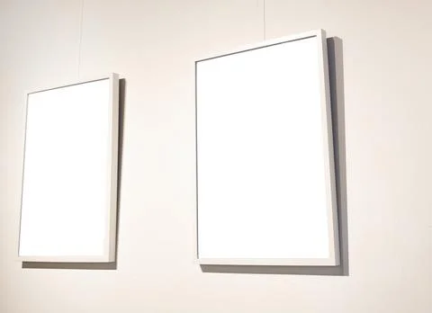 Blank picture frames on grey wall with glowing lamp, mock up Stock Photos