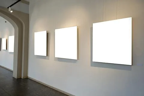 Blank picture frames on grey wall with glowing lamp, mock up Stock Photos