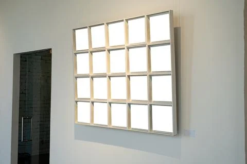 Blank picture frames on grey wall with glowing lamp, mock up Stock Photos
