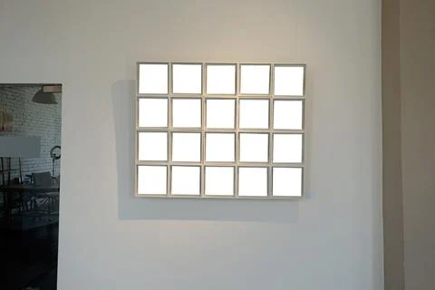Blank picture frames on grey wall with glowing lamp, mock up Stock Photos