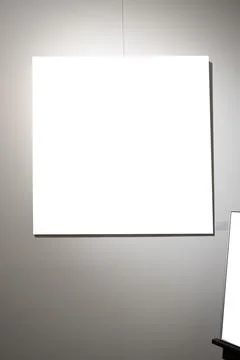 Blank picture frames on grey wall with glowing lamp, mock up Stock Photos