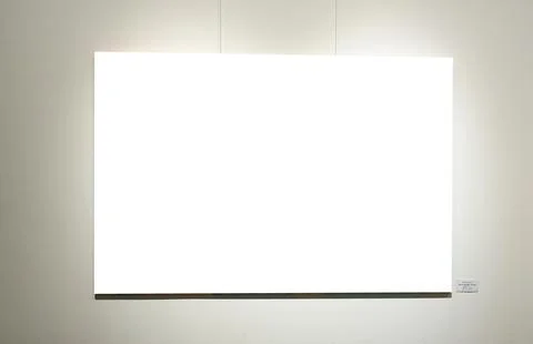 Blank picture frames on grey wall with glowing lamp, mock up Stock Photos