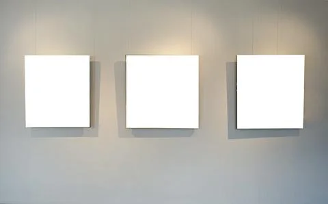 Blank picture frames on grey wall with glowing lamp, mock up Stock Photos