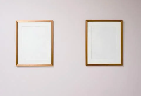 Blank picture frames hanging on an empty wall, providing copy space and a m.. Stock Photos