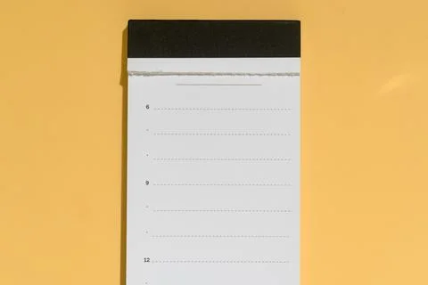 Blank planner sheet with torn top and black header stands on yellow backgroun Stock Photos