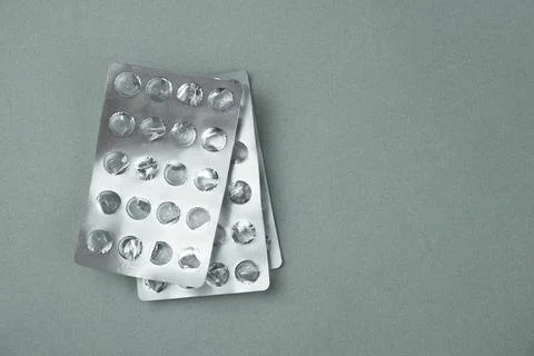 Blank plastic packaging of pills on a gray background. Stock Photos