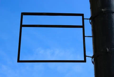 A blank rectangular advertising sign framing a blue sky background. Foto stock