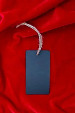 Blank rectangular label on red velvet. Black long tag. Copy space. Place for  Stock Photos
