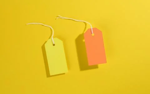 Blank rectangular paper yellow and orange price tags with white rope on yello Stock Photos
