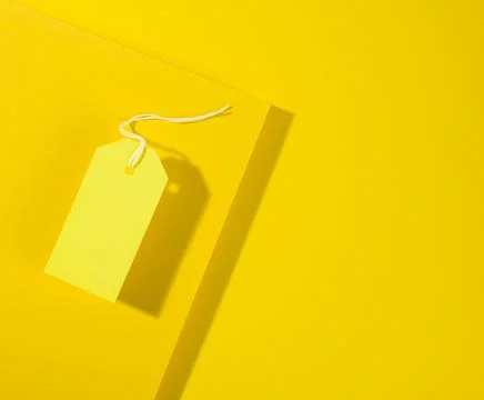 Blank rectangular paper yellow price tag with white rope on yellow background Foto stock