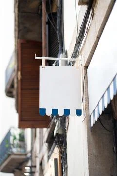 Blank rectangular shop sign blue scalloped edges hanging from a metal bracket 写真素材