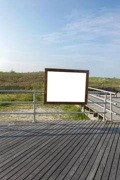 Blank rectangular wooden frame with white center attached to railing on a woo Foto stock
