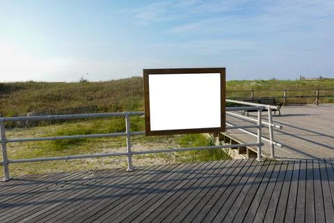 Blank rectangular wooden frame with white center attached to railing on a woo Stockfoto's