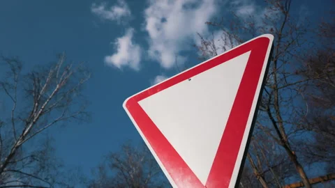 Blank Red and White Triangle Traffic Sign Against Blue Sky 스톡 동영상 334105157