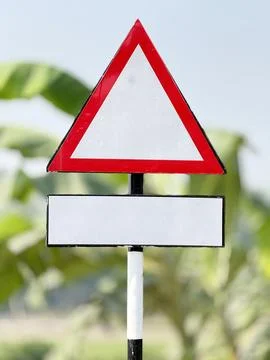 A blank red triangle warning sign stands prominently on a pole with an additi 库存照片
